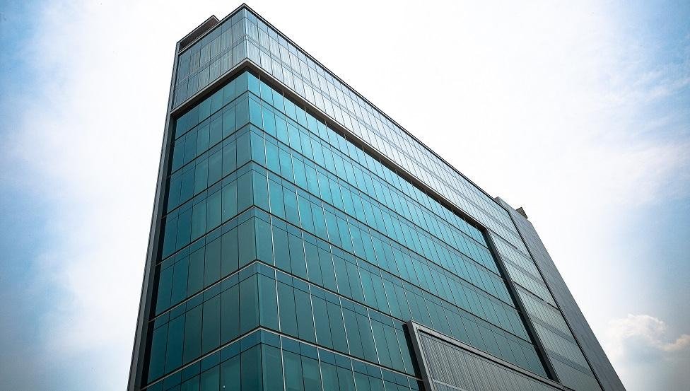 The tinted glass curtain wall of Arihant Verge rising against the sky